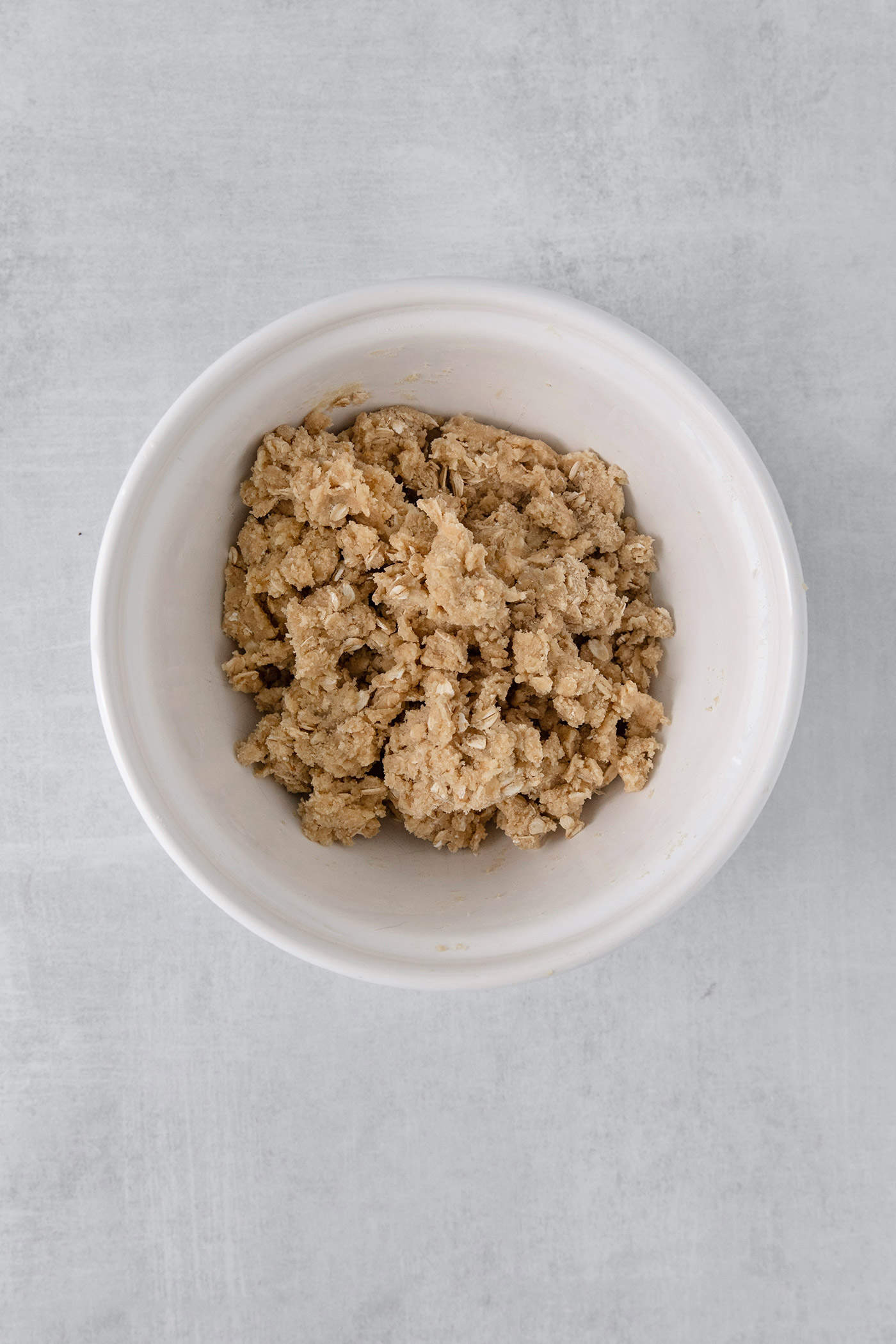 A white bowl with the topping for cranberry apple crisp.