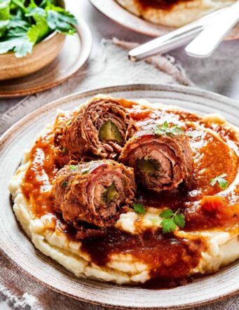 mashed potatoes, gravy, and pieces of rouladen sliced open to reveal the rolled-up interiors