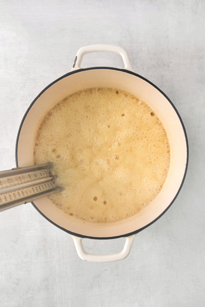 A top down shot of a candy thermometer placed in a pot of fudge.