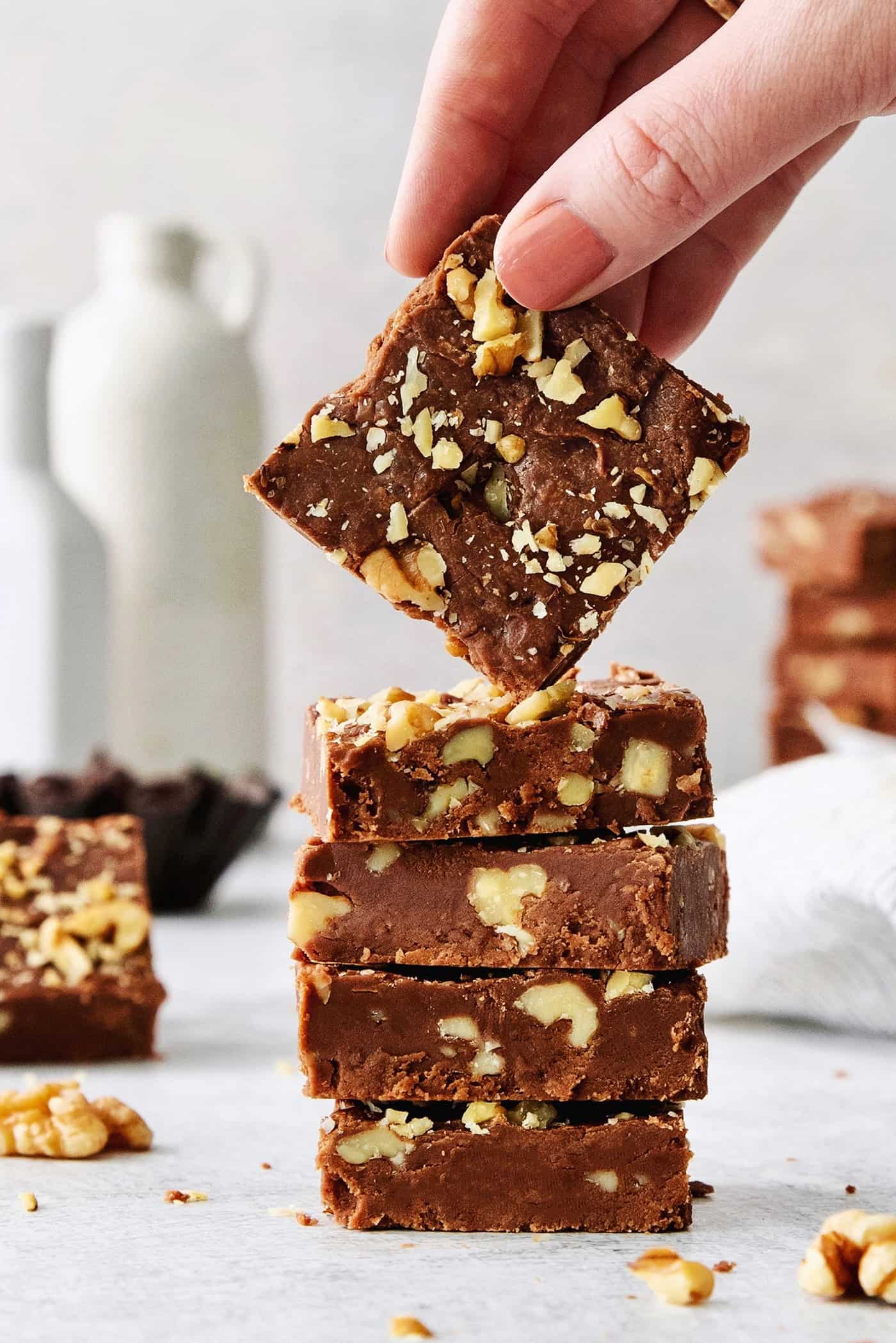 A hand lifts a piece of Fantasy Fudge off the top of a stack of fudge.
