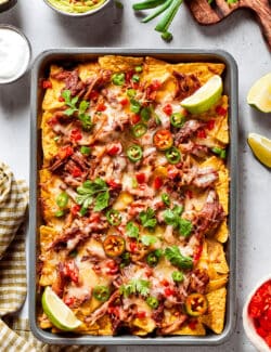 overhead photo of a large rimmed pan of baked nachos with bbq pulled pork