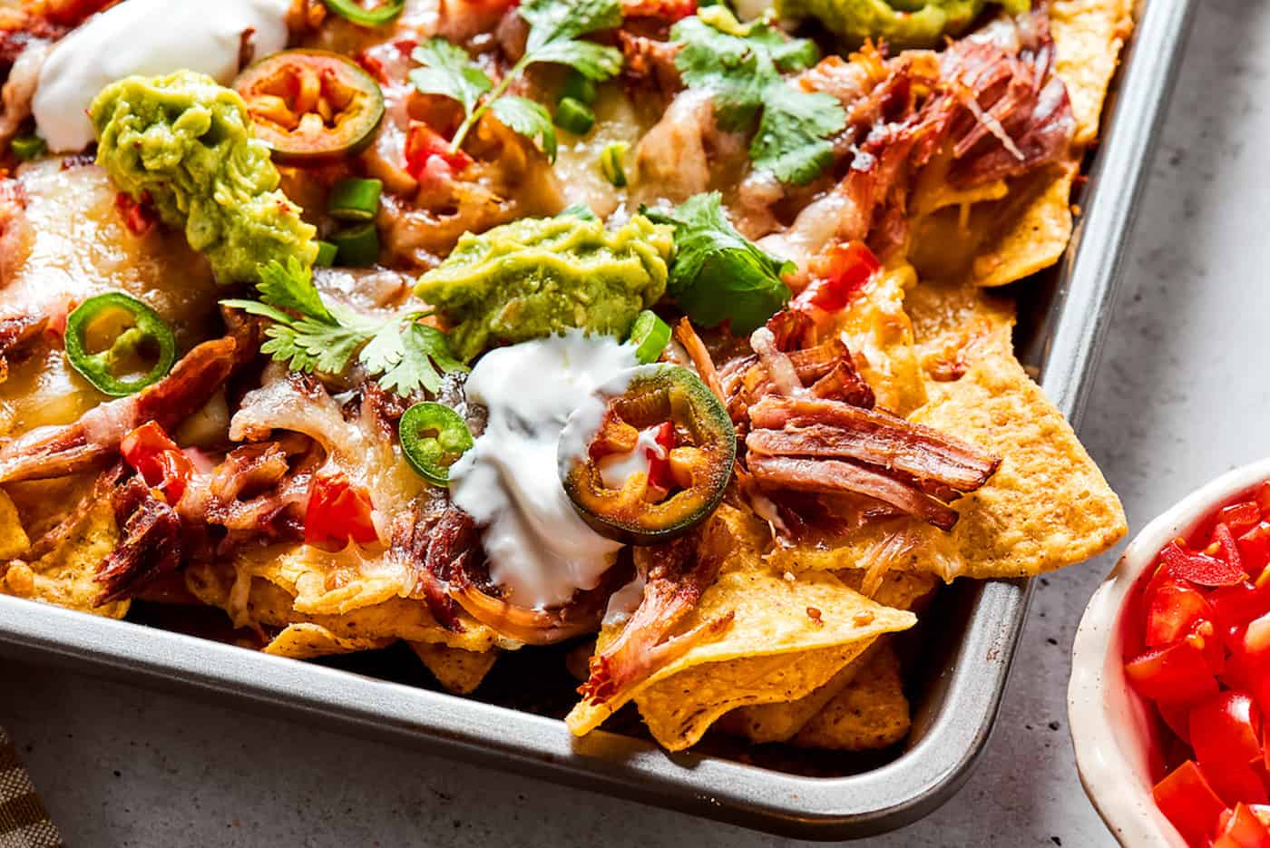 baked nachos with pulled pork on a sheet pan