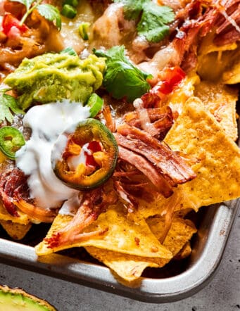 a sheet pan of baked nachos with pulled pork and cheese