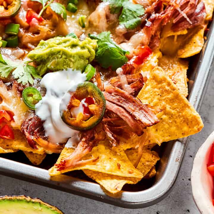 a sheet pan of baked nachos with pulled pork and cheese