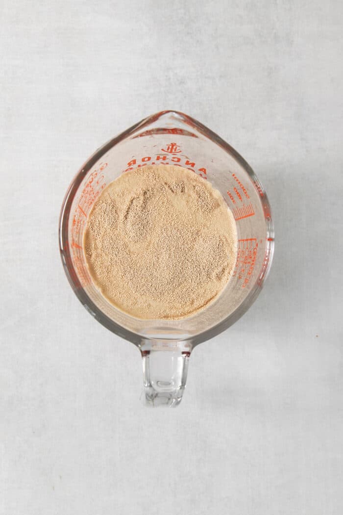 A top down shot of yeast proofing in a glass measuring cup.