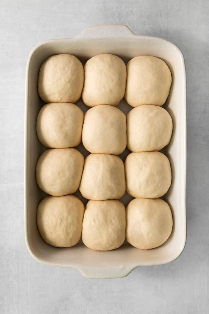 Rolls of proofed dough are shown in a pan to make rhodes rolls.