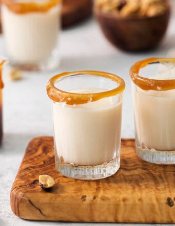 Two salted nut roll shot drinks are shown on a cutting board with more in the background.