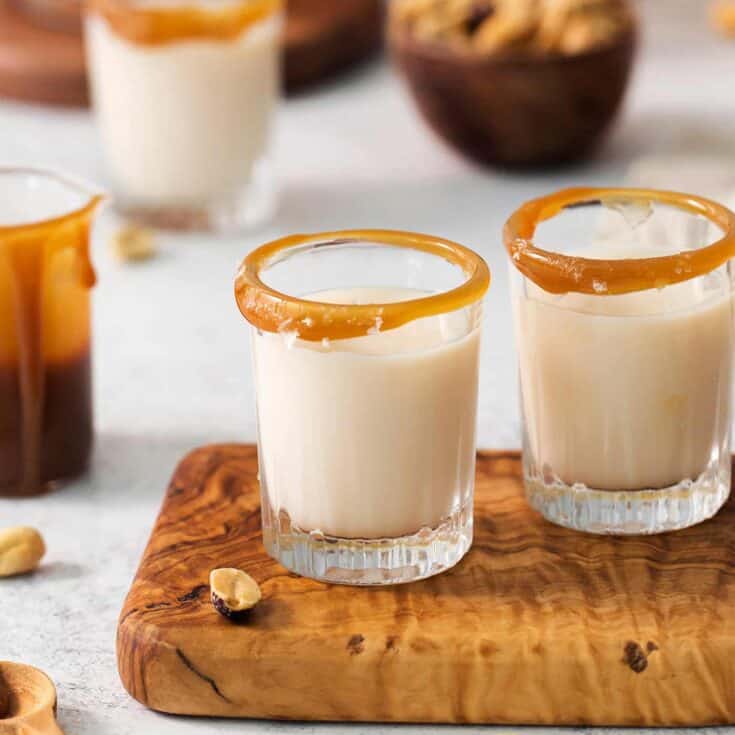 Two salted nut roll shot drinks are shown on a cutting board with more in the background.