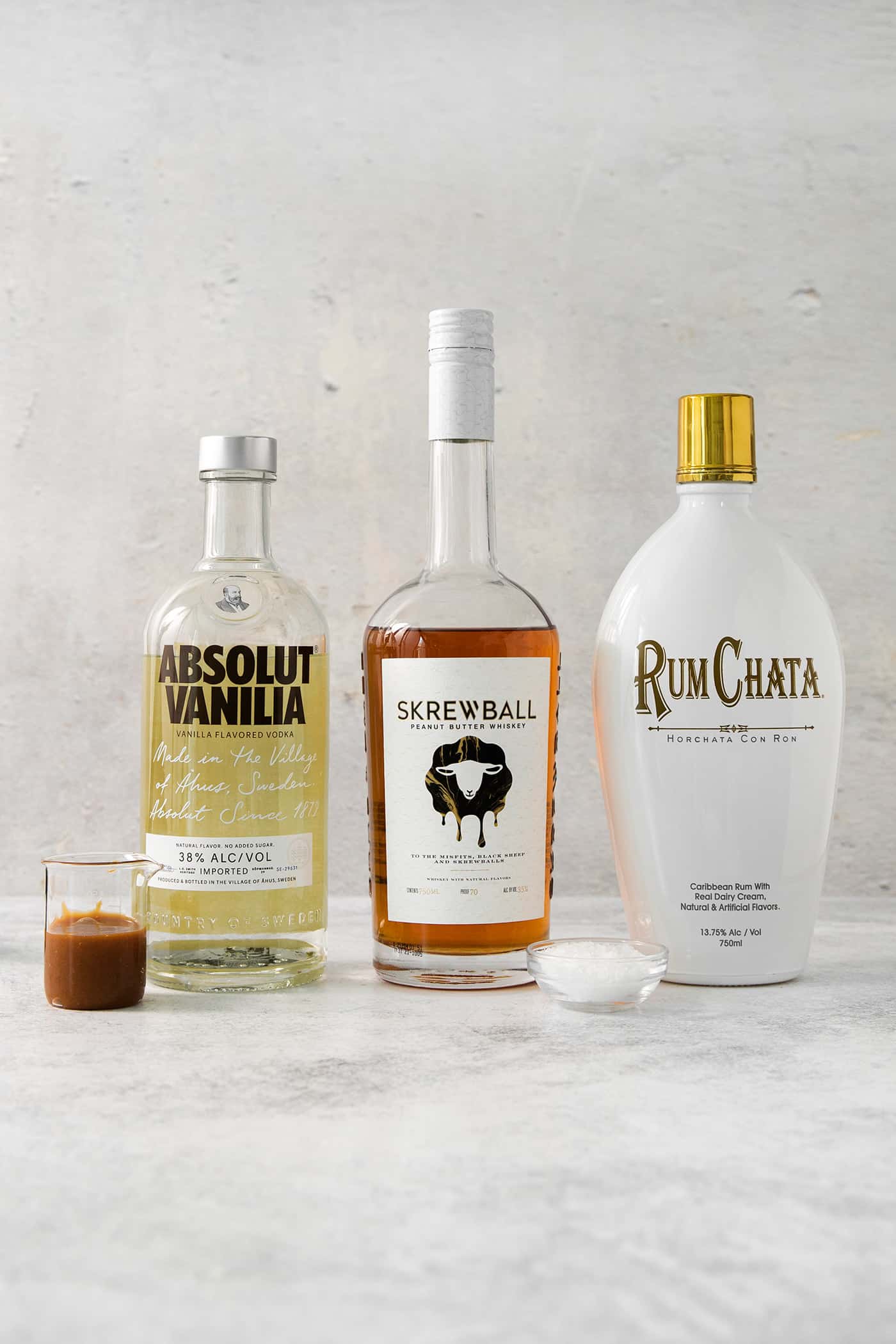 Ingredients for salted nut roll shots are shown: rumchata, peanut butter vodka, and caramel sauce.