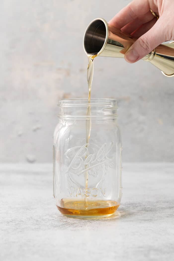 Whiskey is poured into a mason jar.