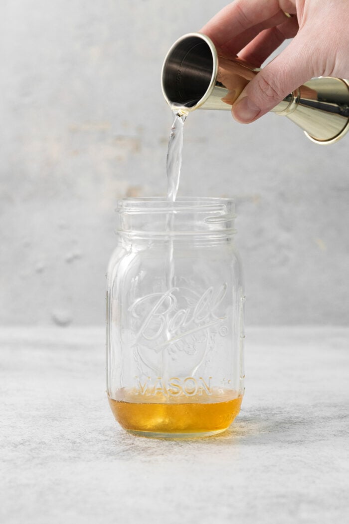 Vodka is poured into a mason jar.