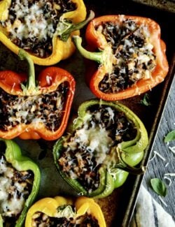 a rimmed pan with bell pepper halves stuffed with wild rice and cheese