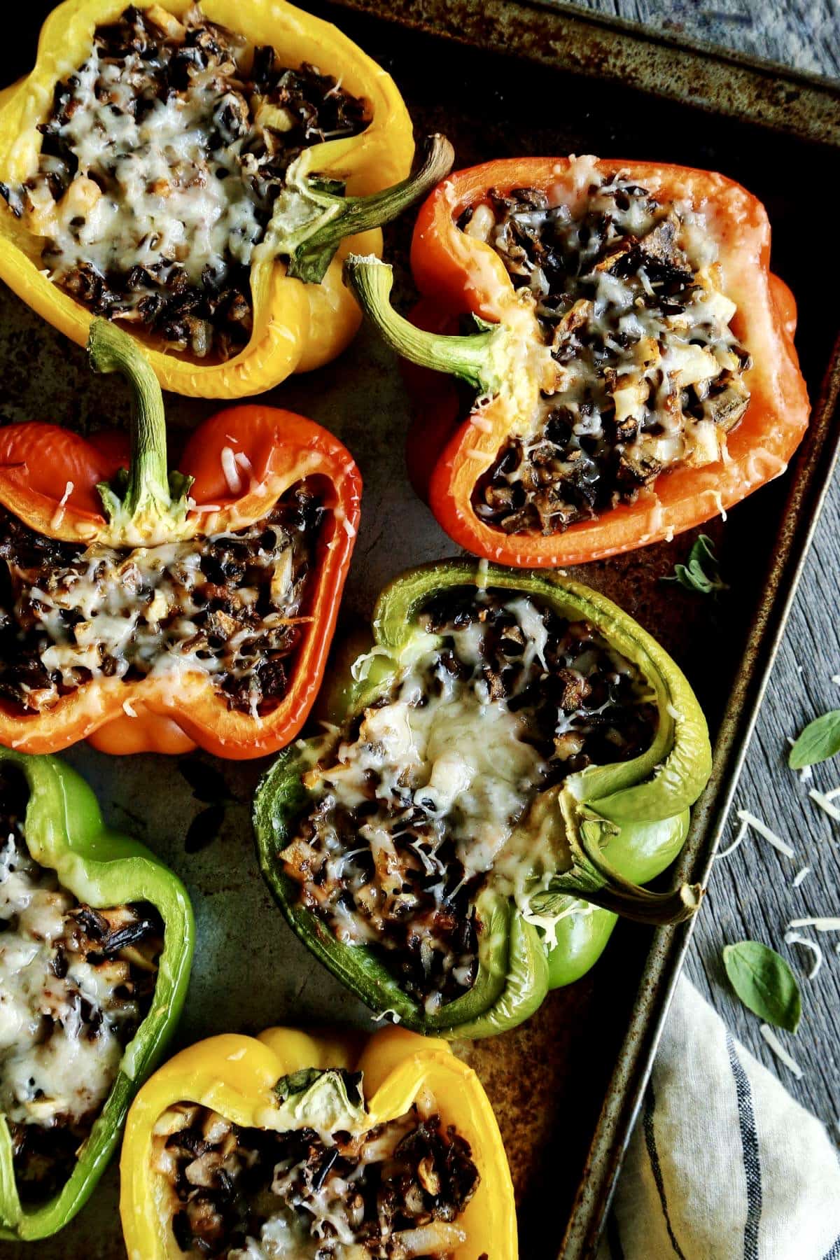 a rimmed pan with bell pepper halves stuffed with wild rice and cheese