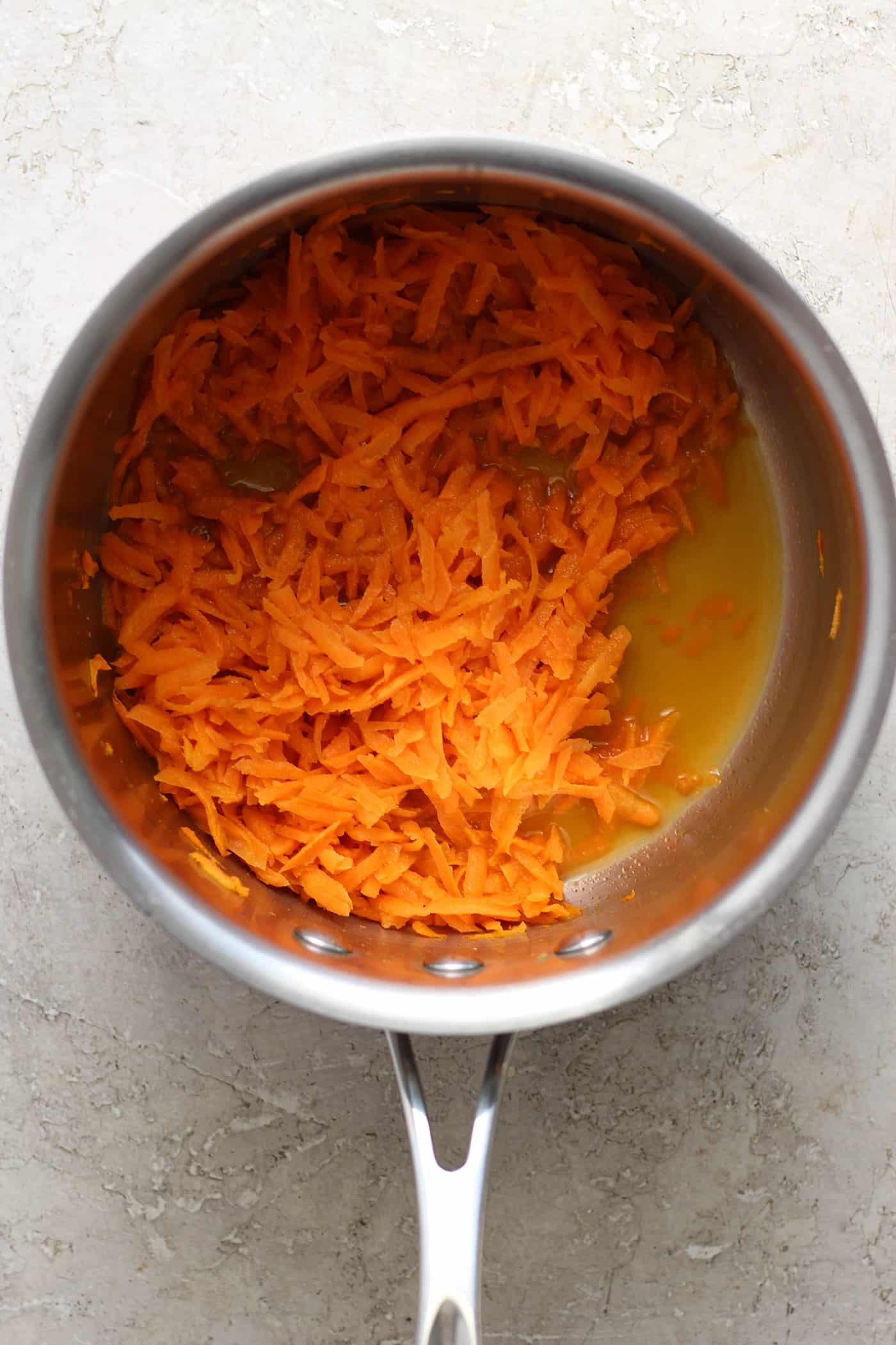 A top down shot of shredded carrots in a pot.