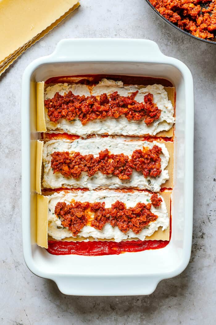 A closer up shot of layers of lasagna pasta topped with cheese filling and meat sauce.