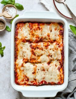 A white baking dish of lasagna roll ups topped with red sauce and melted mozzarella cheese.