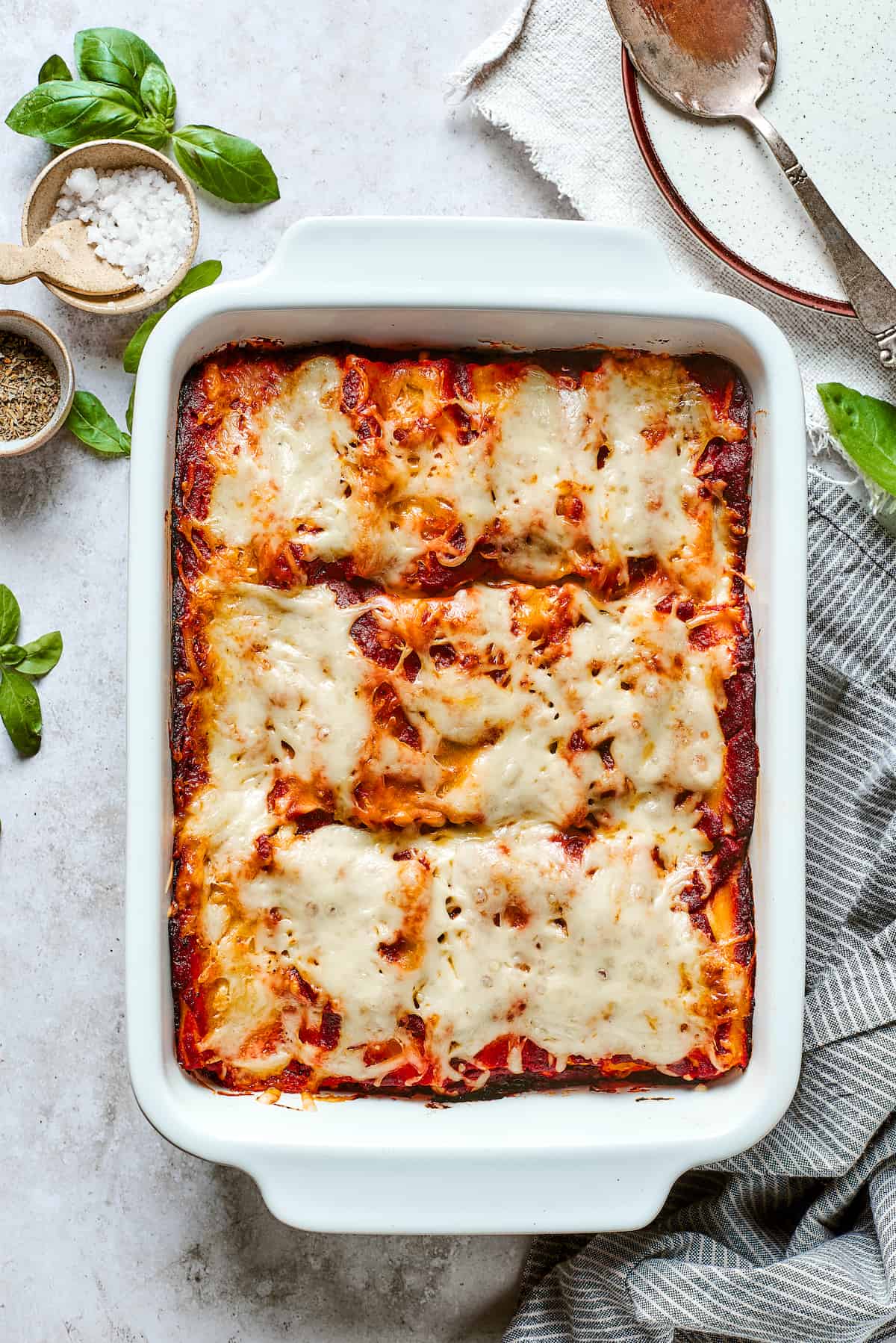 These cheesy Lasagna Roll Ups include a hearty blend of cheeses and sausage-flecked meat sauce that's wrapped in tender noodles. A white baking dish of lasagna roll ups topped with red sauce and melted mozzarella cheese.