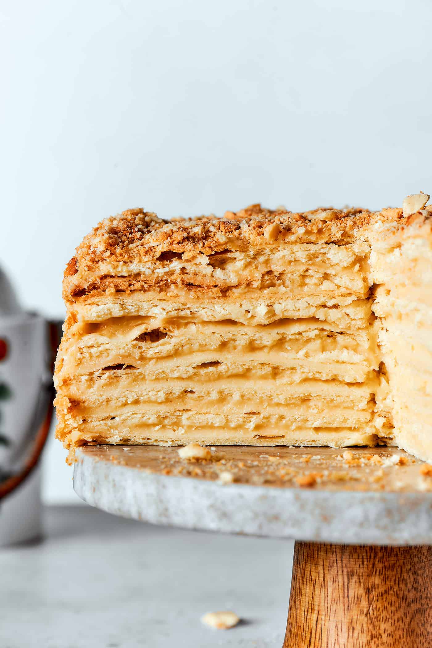 Napoleon cake on a cake stand, cut open to reveal all the layers in the cake