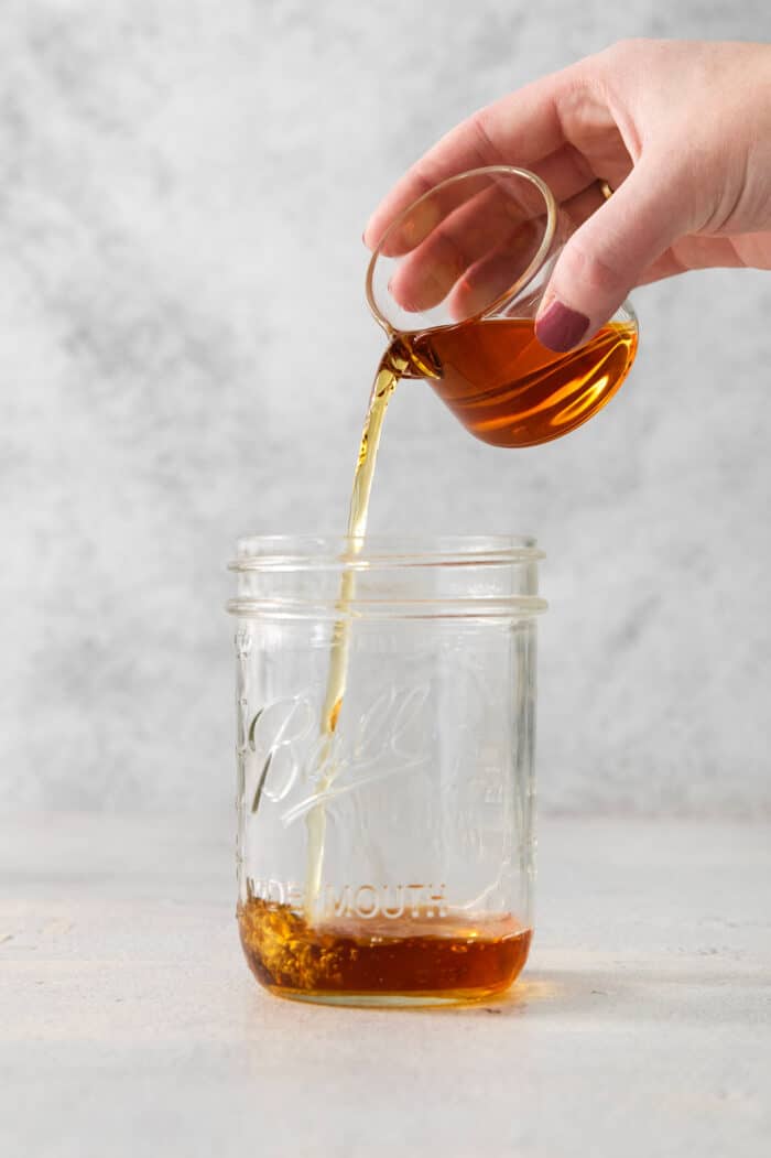 A hand pours brandy into a jar.
