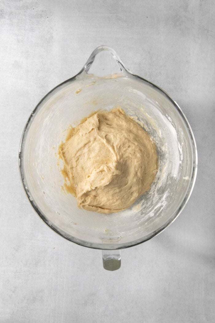 Dough for caramel rolls is formed in a glass bowl.