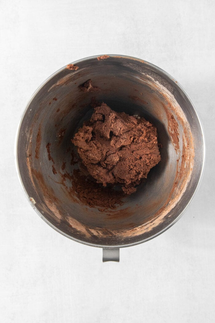 These Chocolate Cream Wafer Cookies feature buttery cocoa cookies that are soft, tender, and filled with a rich buttercream. A metal bowl holds chocolate wafer cookie dough.