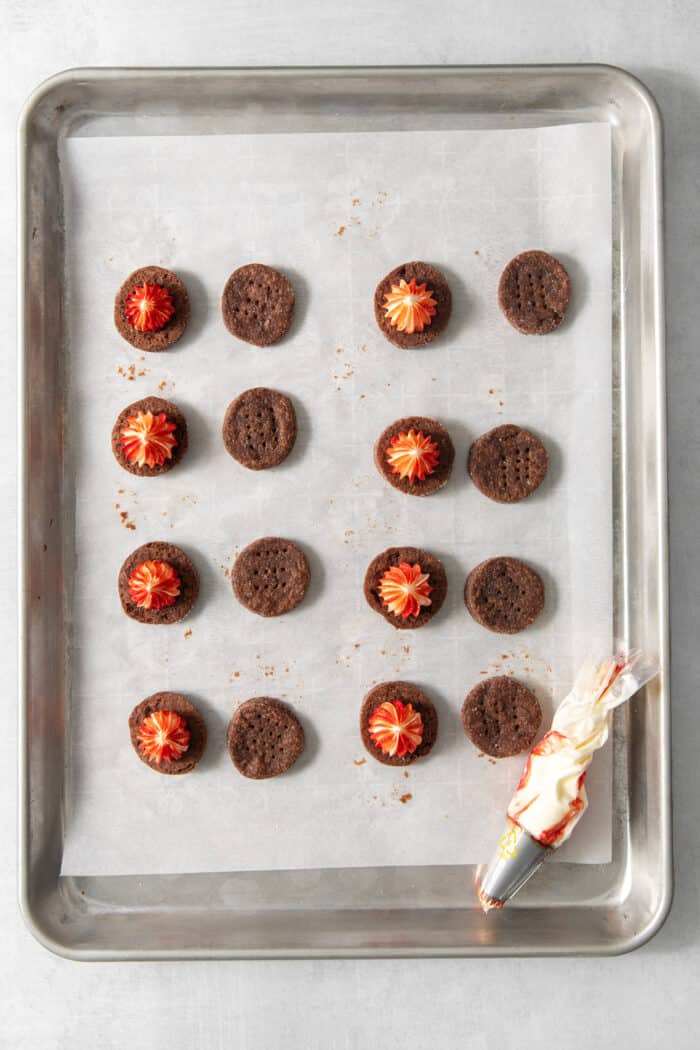 Chocolate cream wafer cookies on a parchment paper lined baking sheet - half are topped with peppermint buttercream filling.