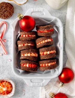 A white dish holds chocolate cream wafer cookies turned on their sides to show the peppermint filling.