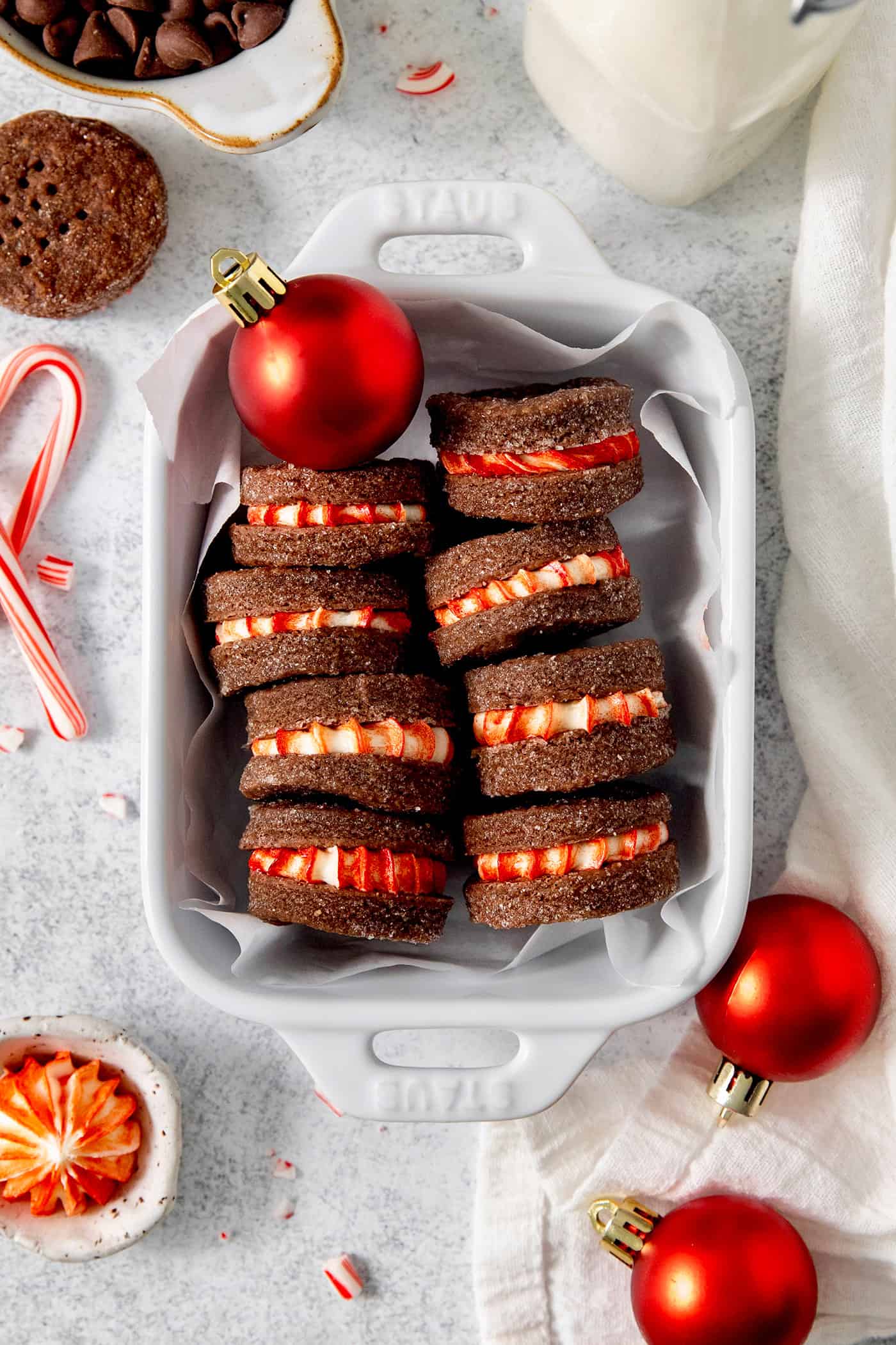 These Chocolate Cream Wafer Cookies feature buttery cocoa cookies that are soft, tender, and filled with a rich buttercream. A white dish holds chocolate cream wafer cookies turned on their sides to show the peppermint filling.