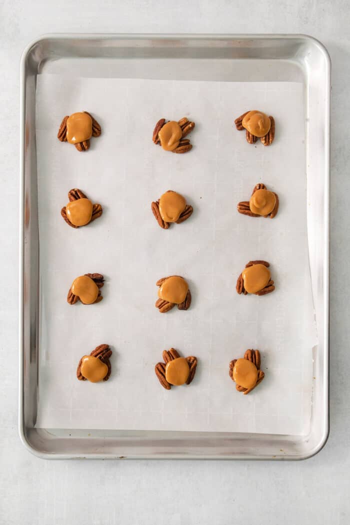 Caramel is placed atop nuts on a baking tray.