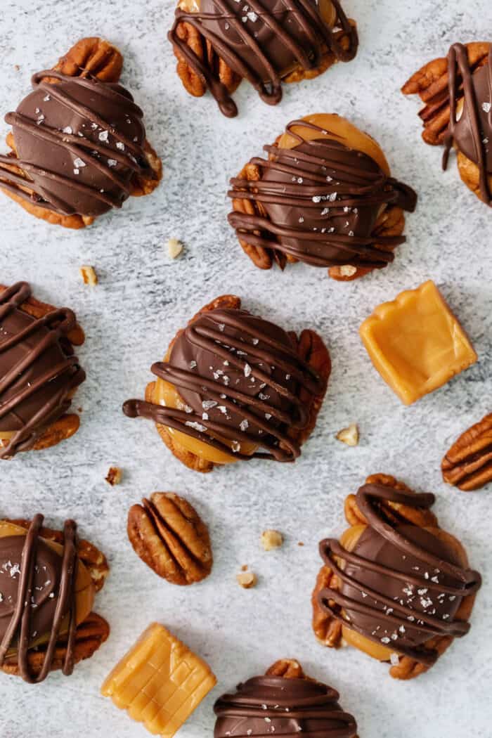 Chocolate turtles are shown on a white background with caramels and pecans.