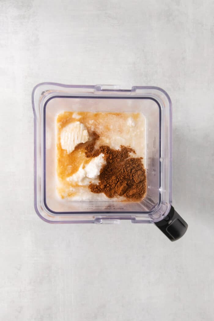 A top down shot of a blender holding coquito ingredients.