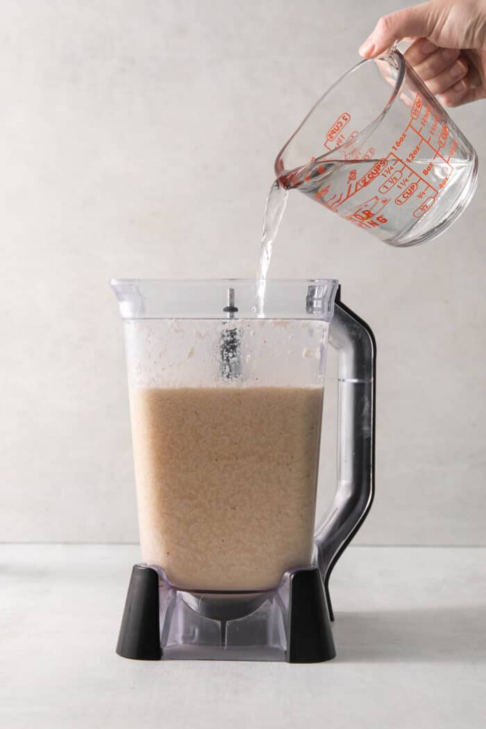 Rum is poured into a blender of coquito mix.