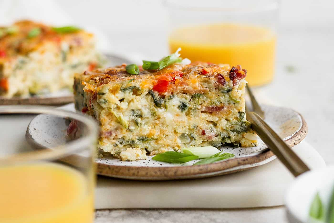 A plate of cottage cheese egg bake with a glass of orange juice.