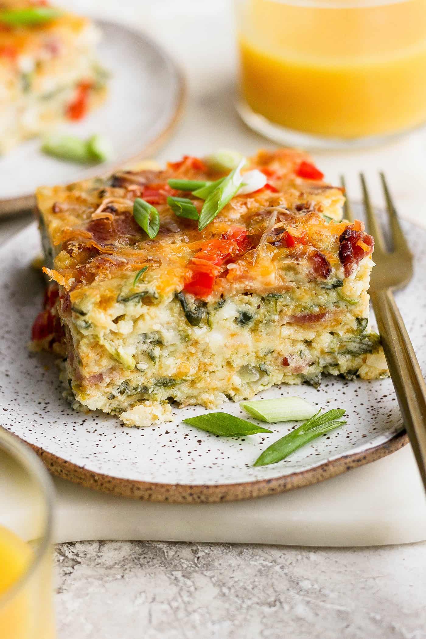 A plate of cottage cheese egg bake with a glass of orange juice.