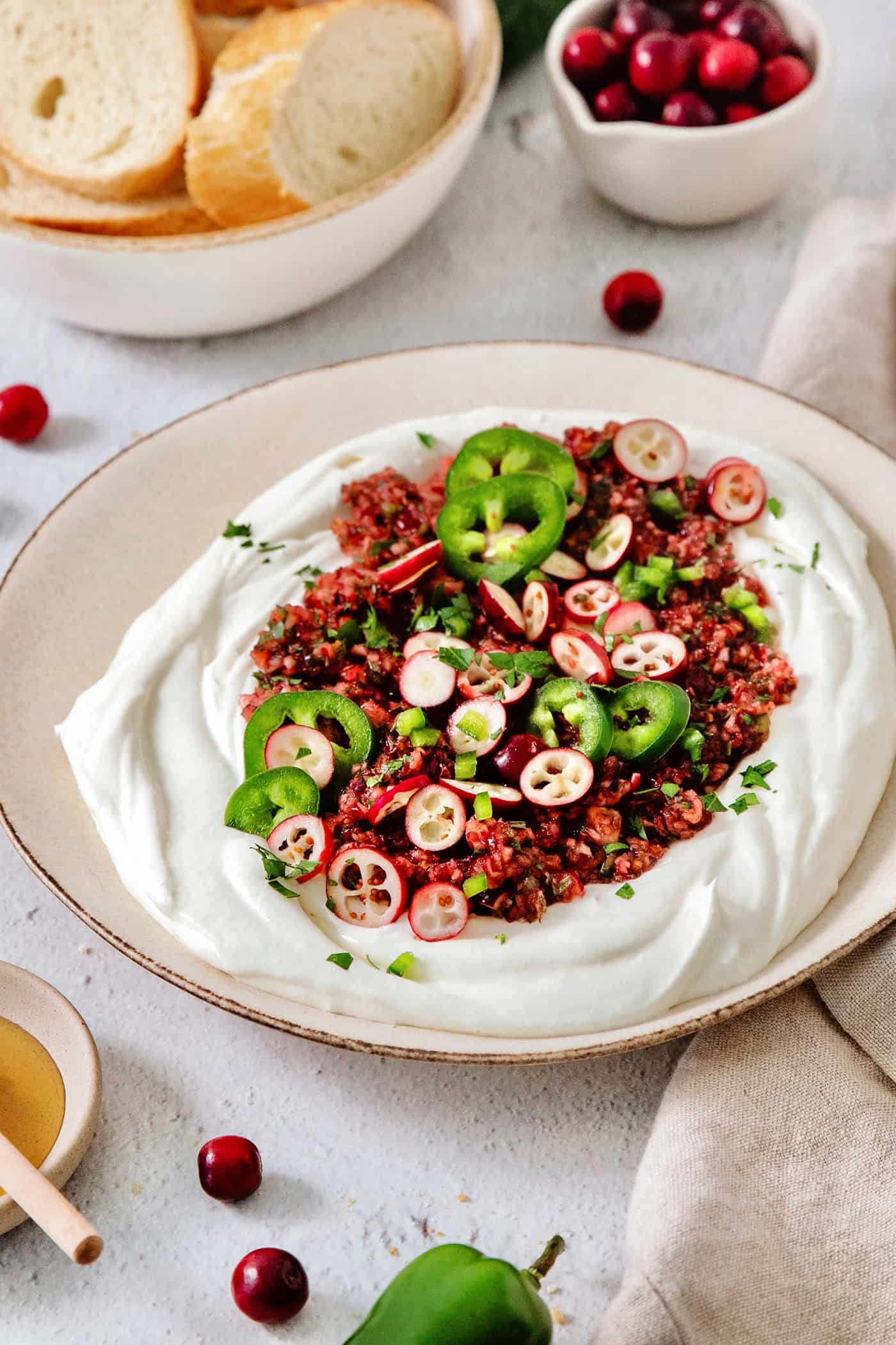 This Cranberry Jalapeno Dip is a quick and easy holiday appetizer! It features cream cheese and goat cheese and a cranberry-jalapeno relish. A bowl of cranberry jalapeno dip.