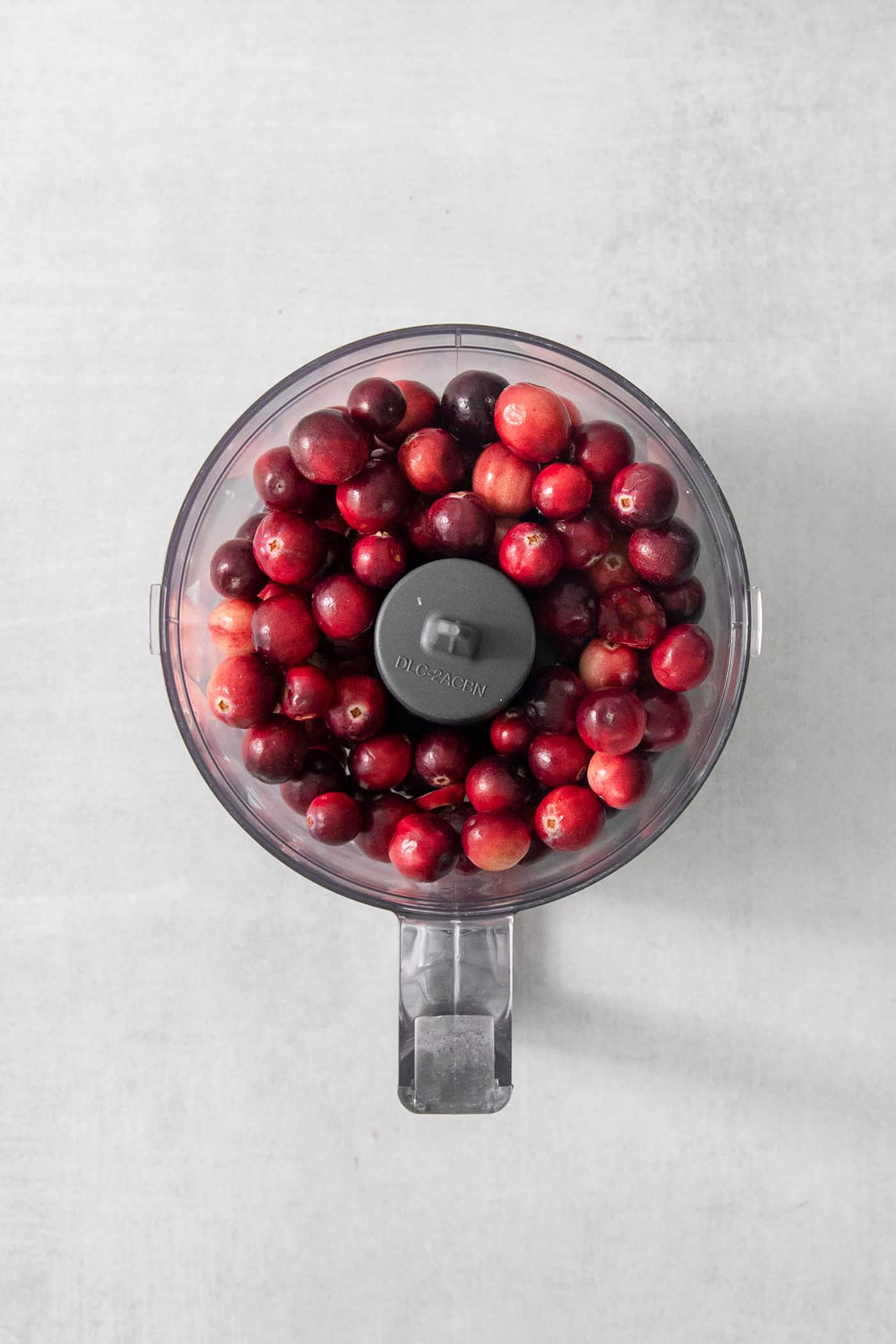 A top down shot of a food processor full of cranberries.