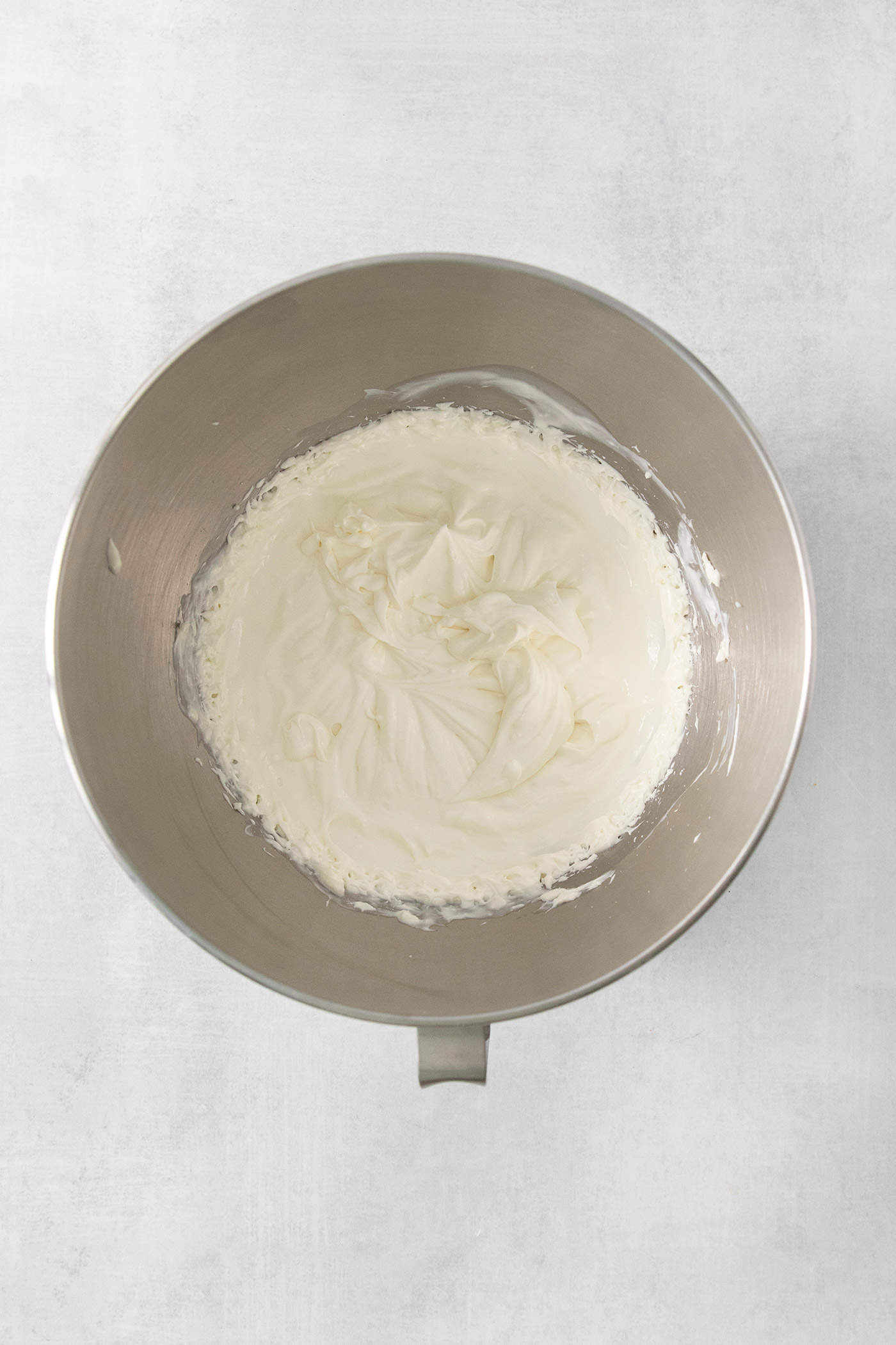 A metal bowl holds a blend of cream, cream cheese, and goat cheese.