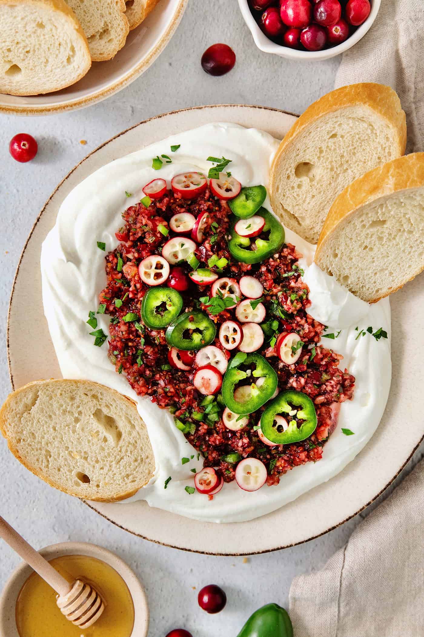 A top down shot of a bowl of cranberry jalapeno dip and slices of bread.