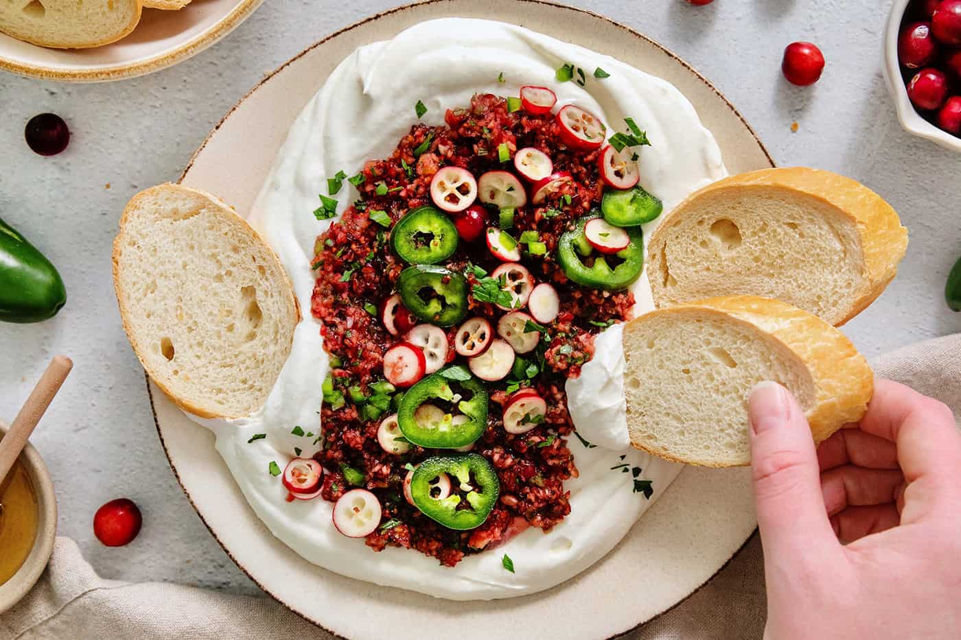 A top down shot of a bowl of cranberry jalapeno dip and slices of bread.