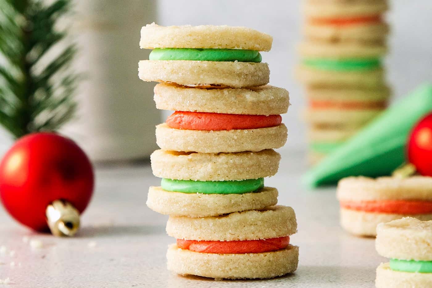 A stack of cream wafter cookies with red and green filling.