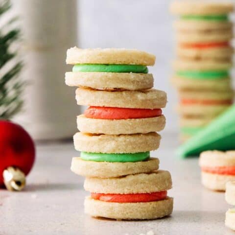 A stack of cream wafter cookies with red and green filling.