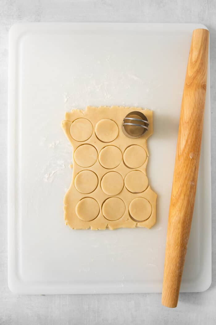 Cream wafer cookie dough is shown with a circular cutter and a rolling pin.