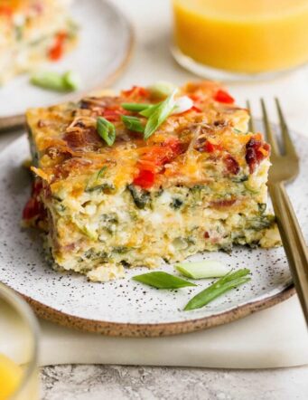 A plate of cottage cheese egg bake with a glass of orange juice.