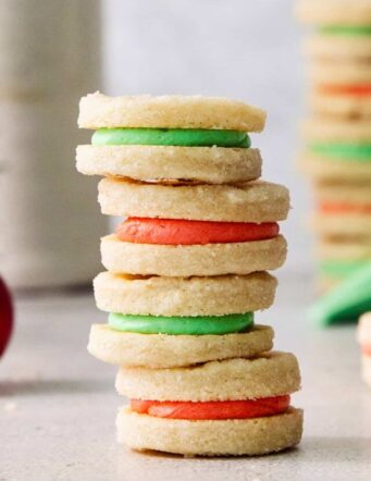 A stack of cream wafter cookies with red and green filling.
