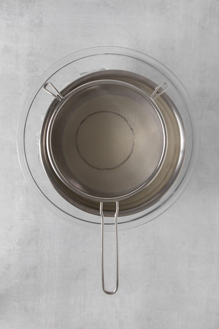 A strainer is set above a metal bowl.