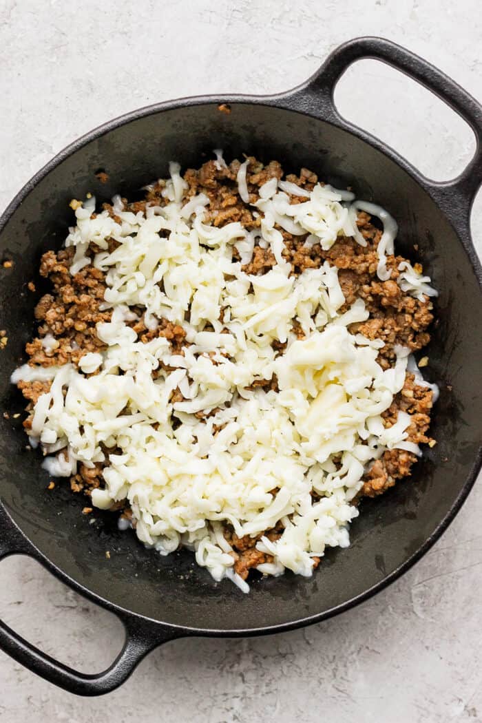 Cooked chorizo is topped with a layer of shredded oaxaca cheese.