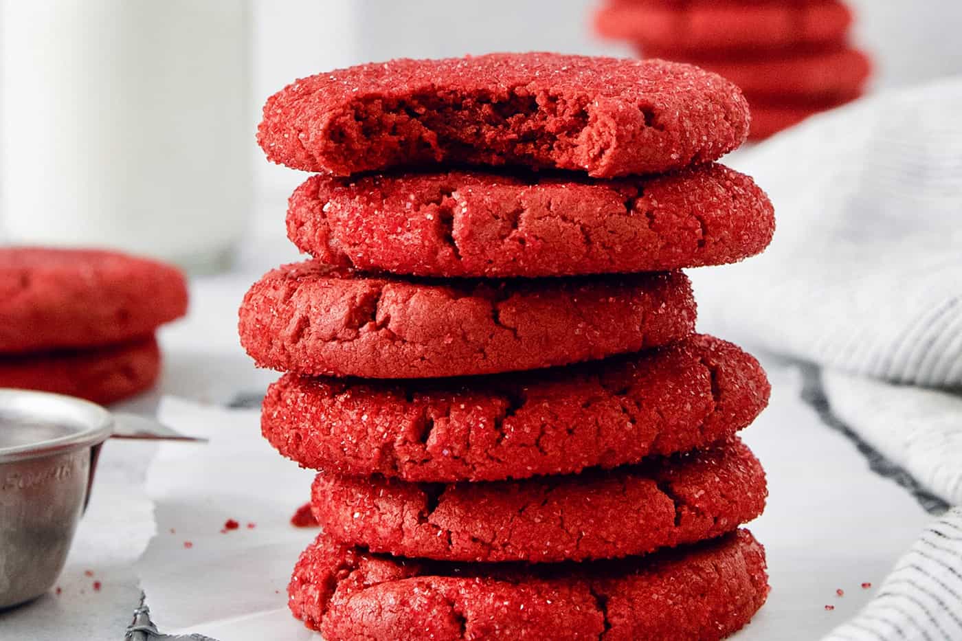 A stack of red velvet cookies, with the top cookie having a bite taken out.