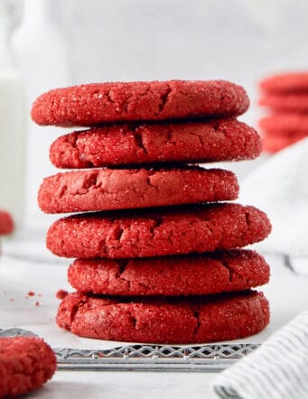A stack of red velvet cookies with more cookies in the background.
