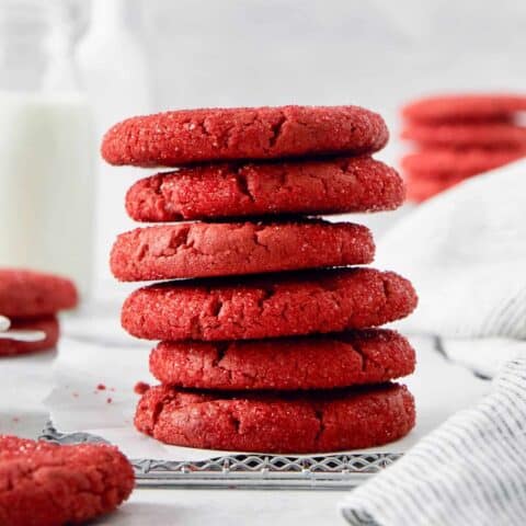 A stack of red velvet cookies with more cookies in the background.