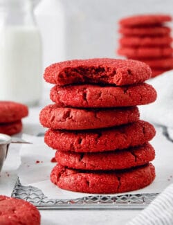 A stack of red velvet cookies, with the top cookie having a bite taken out.